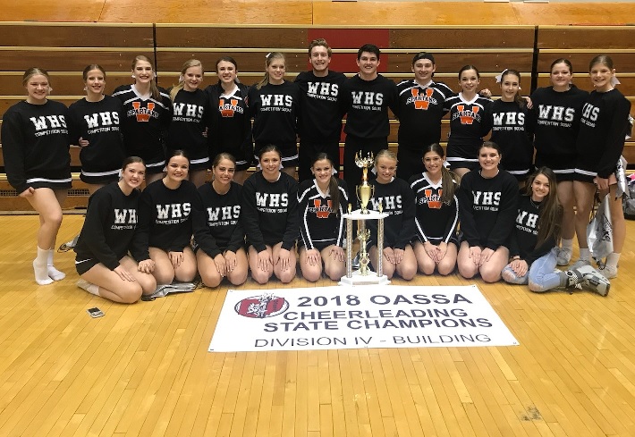 cheerleading team with a trophy and banner